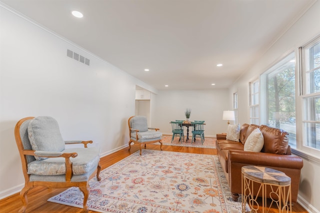 sitting room featuring visible vents, ornamental molding, baseboards, and wood finished floors