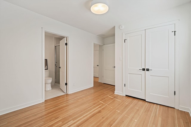 unfurnished bedroom with ensuite bath, light wood-style floors, baseboards, and a closet