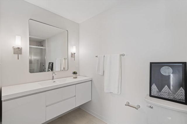 bathroom with vanity, toilet, baseboards, and a stall shower