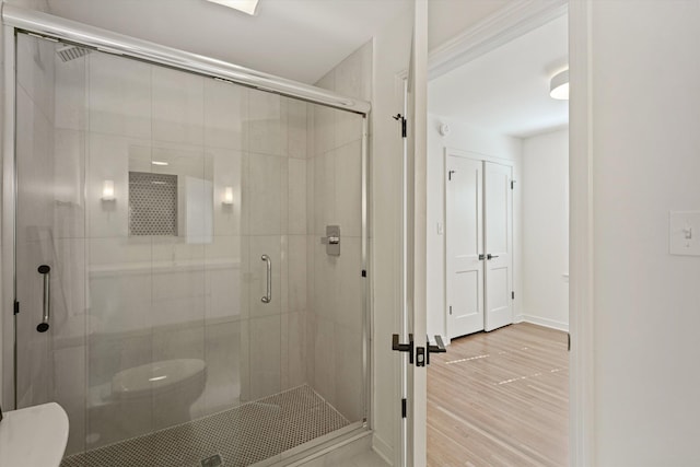 full bathroom featuring a stall shower, baseboards, toilet, and wood finished floors