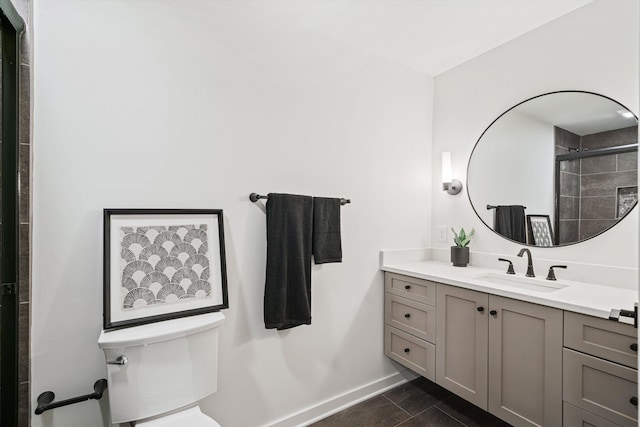 bathroom with vanity, baseboards, a tile shower, tile patterned flooring, and toilet