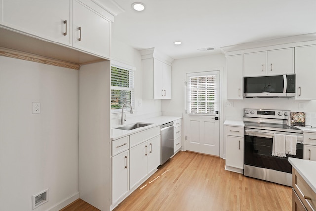 kitchen featuring a sink, stainless steel appliances, a healthy amount of sunlight, and light wood finished floors