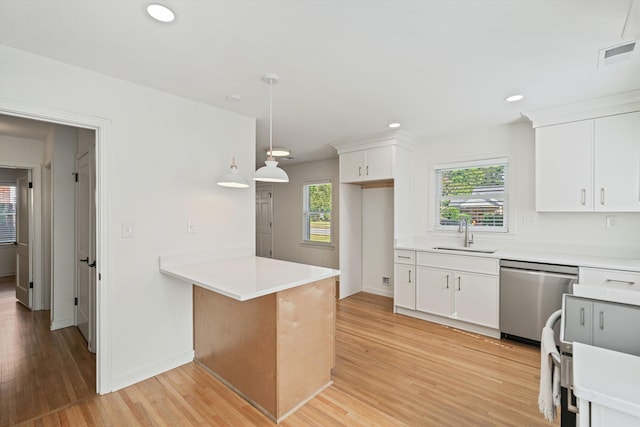 kitchen with stainless steel dishwasher, light countertops, visible vents, and a sink