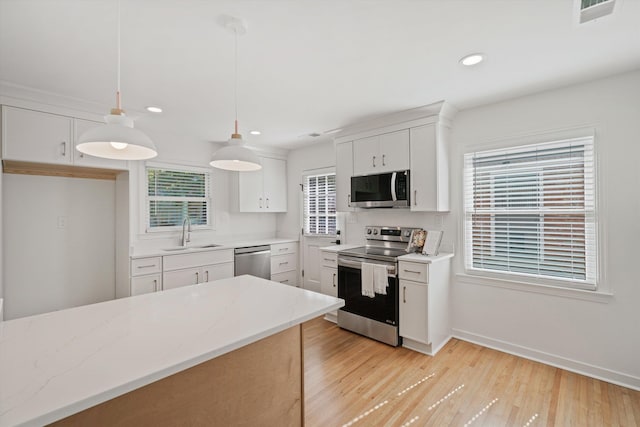 kitchen featuring visible vents, a sink, stainless steel appliances, white cabinets, and light wood finished floors