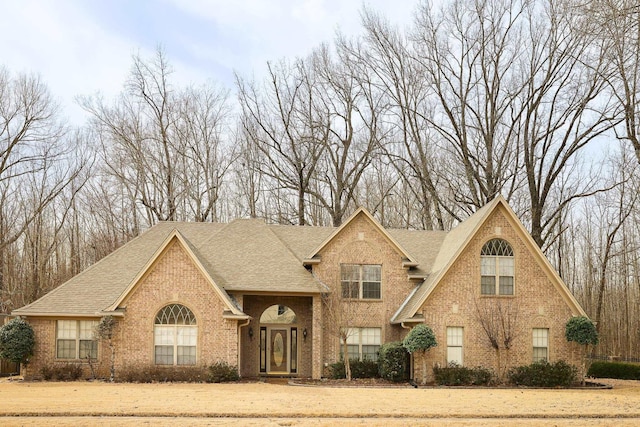 view of front facade with brick siding and a shingled roof