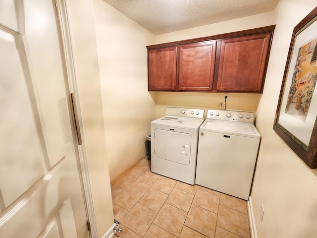 laundry area featuring washer and dryer, a textured ceiling, cabinet space, light tile patterned floors, and baseboards