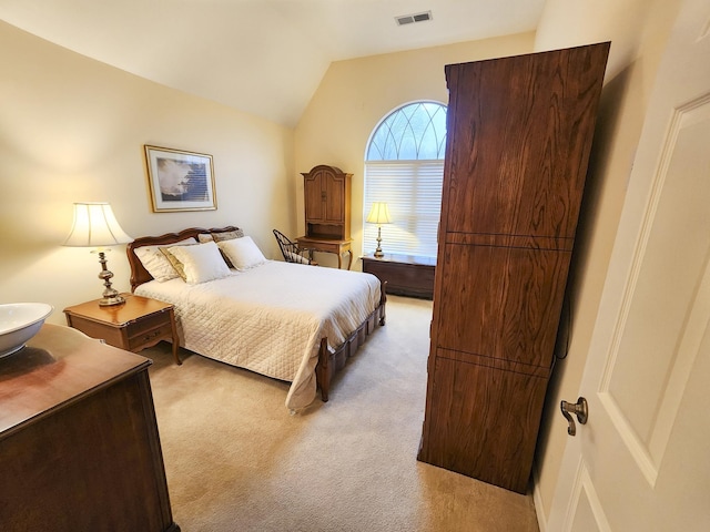 bedroom with visible vents, lofted ceiling, and light colored carpet