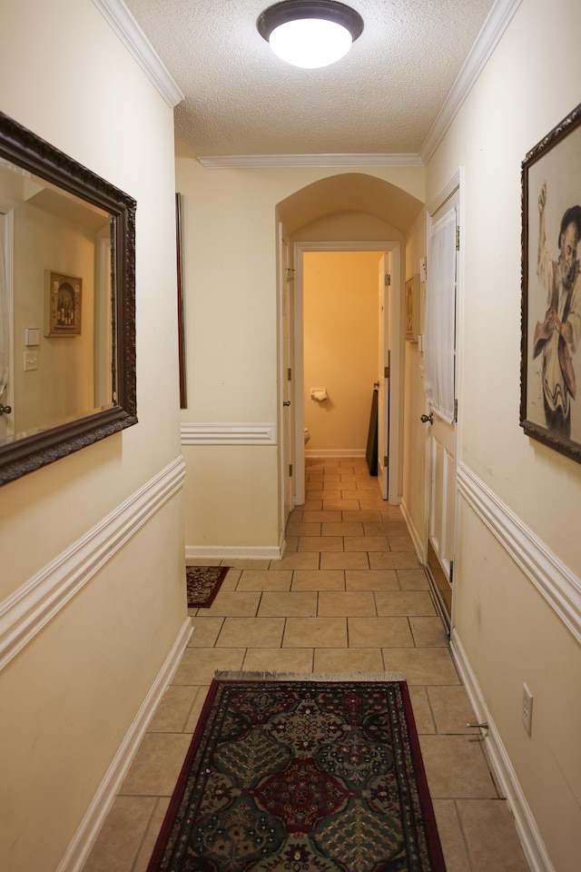 corridor featuring arched walkways, a textured ceiling, and light tile patterned flooring