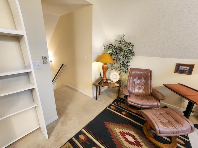 living area with an upstairs landing, vaulted ceiling, baseboards, and carpet floors