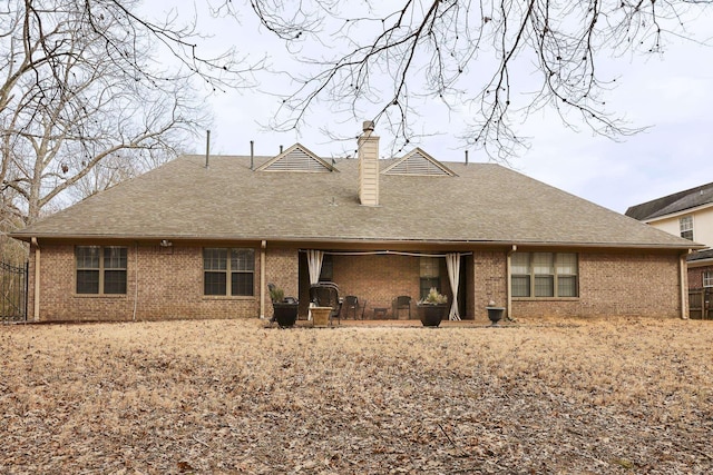 rear view of property with brick siding, a chimney, and roof with shingles