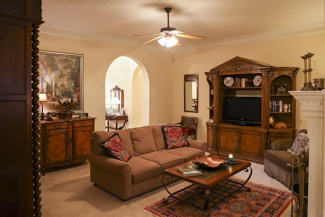 carpeted living room with arched walkways, ornamental molding, and a ceiling fan