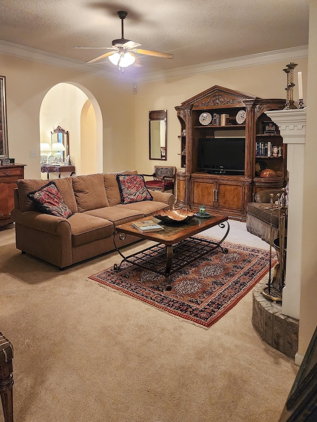 carpeted living area featuring arched walkways, a textured ceiling, ceiling fan, and ornamental molding