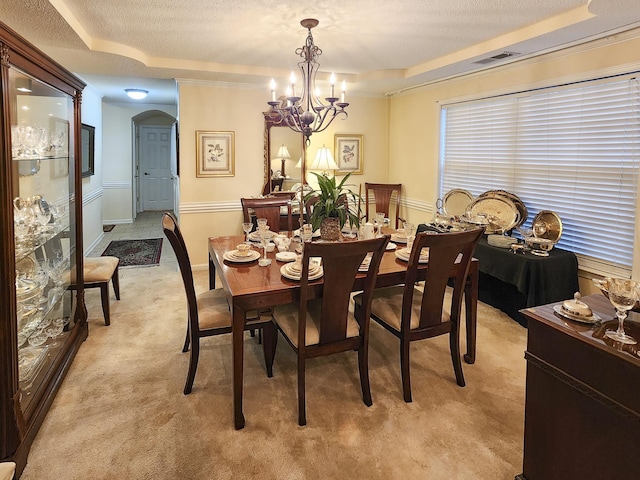 dining room featuring visible vents, a textured ceiling, arched walkways, a raised ceiling, and light colored carpet