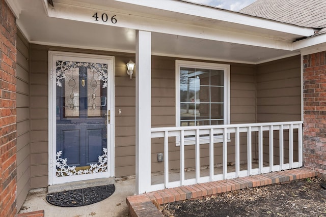 doorway to property featuring brick siding and a porch