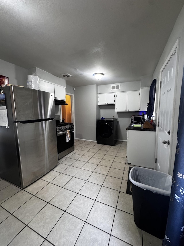 kitchen with visible vents, washer / clothes dryer, freestanding refrigerator, light tile patterned floors, and gas range