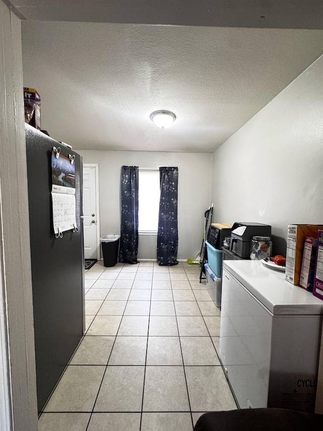 washroom with laundry area, light tile patterned floors, and a textured ceiling