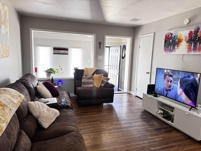 living area with dark wood finished floors, visible vents, and a textured ceiling