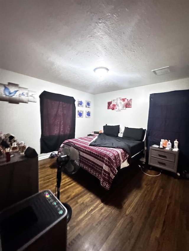 bedroom with a textured ceiling and wood finished floors