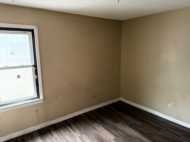 spare room with baseboards, a textured ceiling, and dark wood finished floors