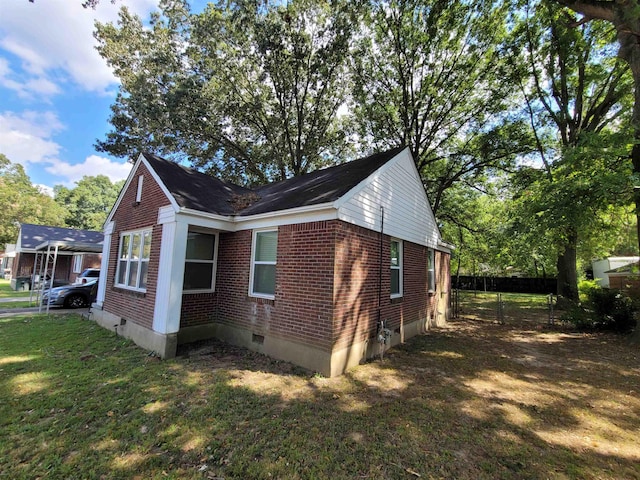 view of side of property with crawl space, brick siding, a lawn, and fence