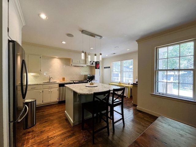 kitchen with a sink, a kitchen island, freestanding refrigerator, crown molding, and dishwasher