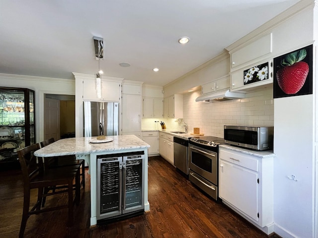 kitchen featuring a sink, wine cooler, appliances with stainless steel finishes, backsplash, and a center island