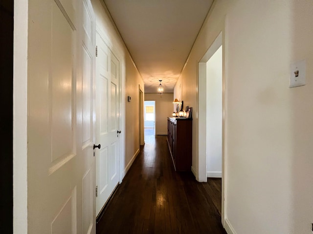 hall with dark wood-type flooring and baseboards