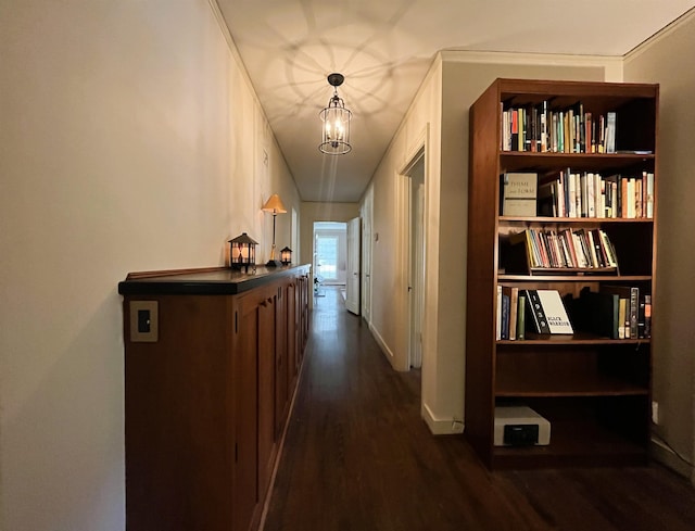 hallway with a notable chandelier, baseboards, and dark wood-type flooring