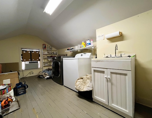 washroom with light wood-style flooring, cooling unit, washing machine and dryer, and a sink