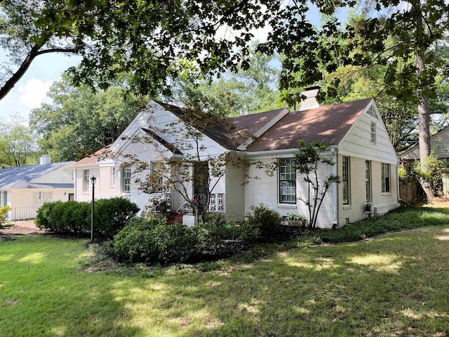 view of front of house featuring brick siding, a chimney, and a front lawn