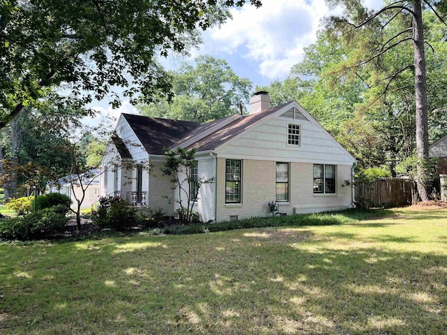 bungalow-style home featuring brick siding, a chimney, a front yard, and fence