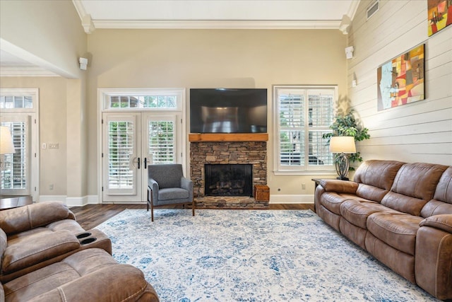 living area with ornamental molding, a fireplace, baseboards, and wood finished floors