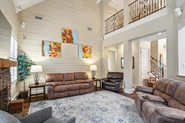 living room featuring wood finished floors, visible vents, baseboards, stairs, and a towering ceiling