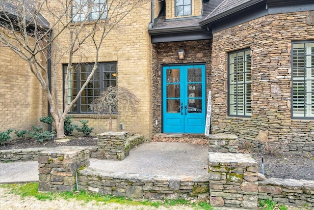 entrance to property with stone siding and roof with shingles