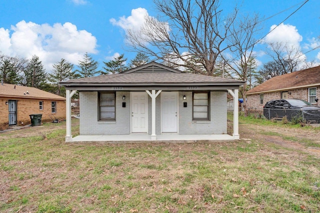 exterior space featuring a front yard, a porch, fence, and brick siding