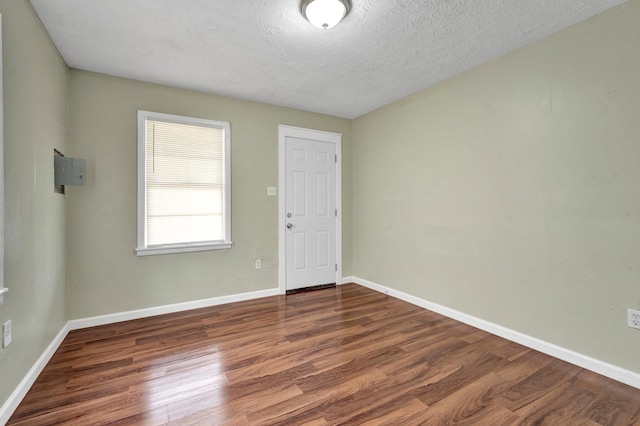 empty room featuring baseboards, a textured ceiling, and wood finished floors