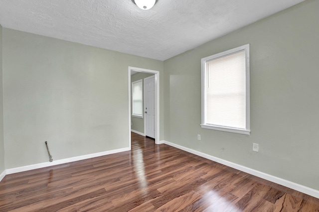 spare room featuring a textured ceiling, baseboards, and wood finished floors