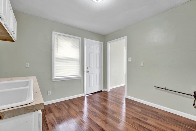 interior space with a sink, baseboards, and wood finished floors