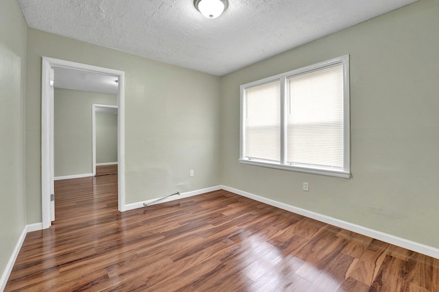 unfurnished room featuring baseboards, a textured ceiling, and dark wood-style flooring