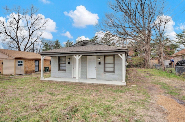 exterior space featuring brick siding, a porch, a lawn, and fence