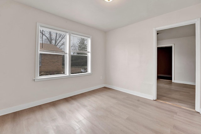 empty room with baseboards and light wood-type flooring