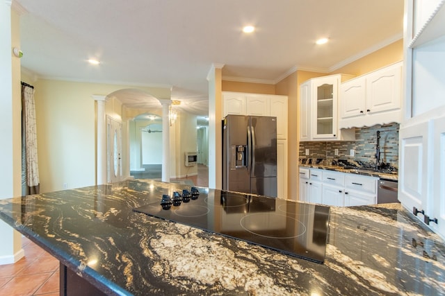 kitchen featuring tasteful backsplash, appliances with stainless steel finishes, arched walkways, white cabinets, and ornate columns