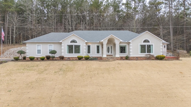 view of front facade featuring a shingled roof, stucco siding, and crawl space