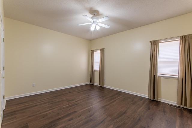 spare room with visible vents, baseboards, dark wood finished floors, and a ceiling fan