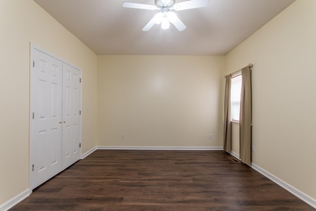 unfurnished bedroom with a ceiling fan, dark wood-style floors, baseboards, and a closet