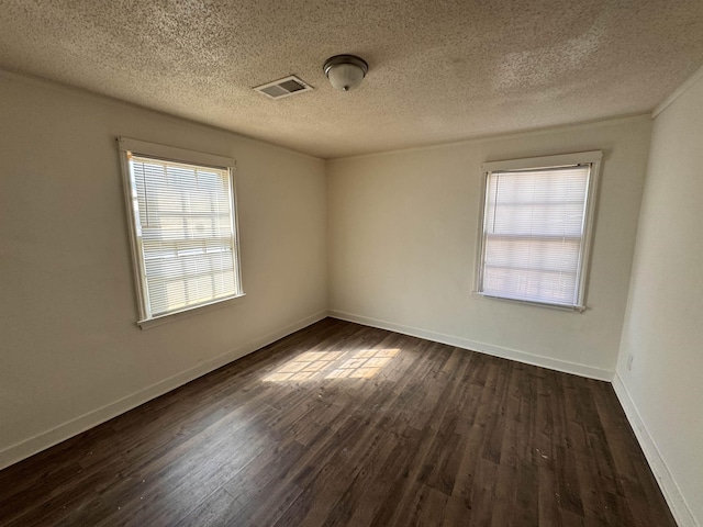 unfurnished room with visible vents, a textured ceiling, baseboards, and dark wood-style flooring