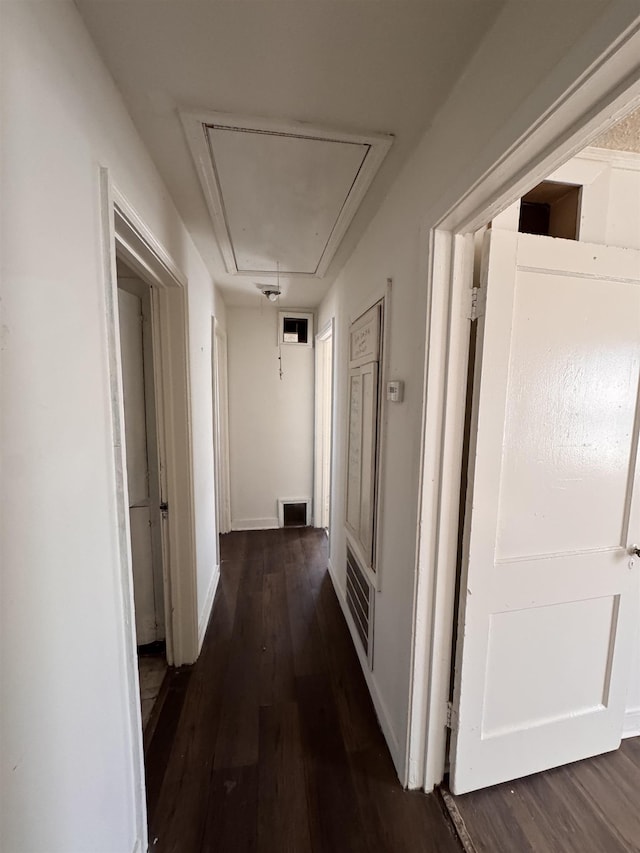 hall featuring visible vents, baseboards, attic access, and dark wood-style floors