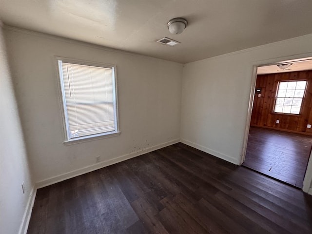 unfurnished room with visible vents, baseboards, and dark wood-type flooring