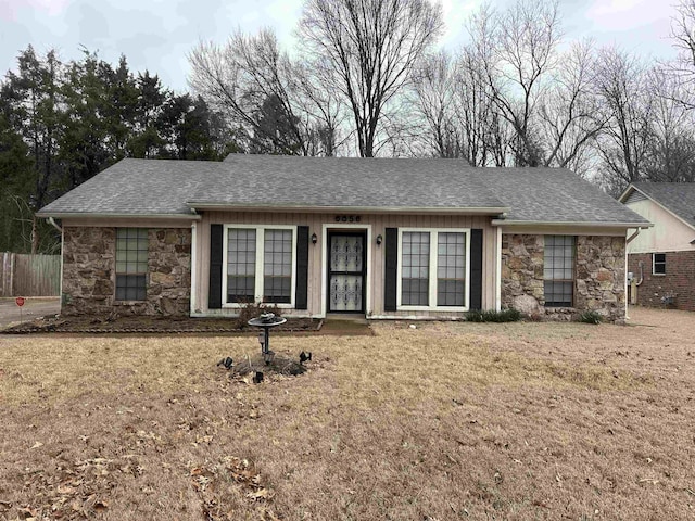 ranch-style home featuring stone siding, a shingled roof, and a front lawn