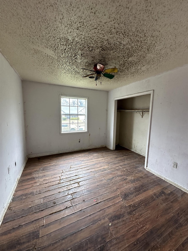 unfurnished bedroom featuring a closet, wood-type flooring, a textured ceiling, and ceiling fan